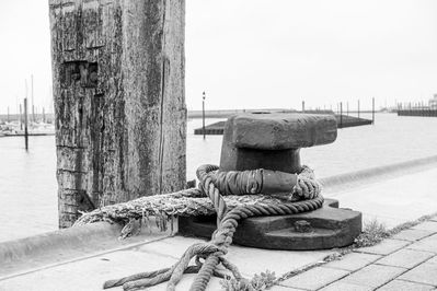 Klampe zum Festmachen von großen Schiffen neben einem verwitterten Pfahl